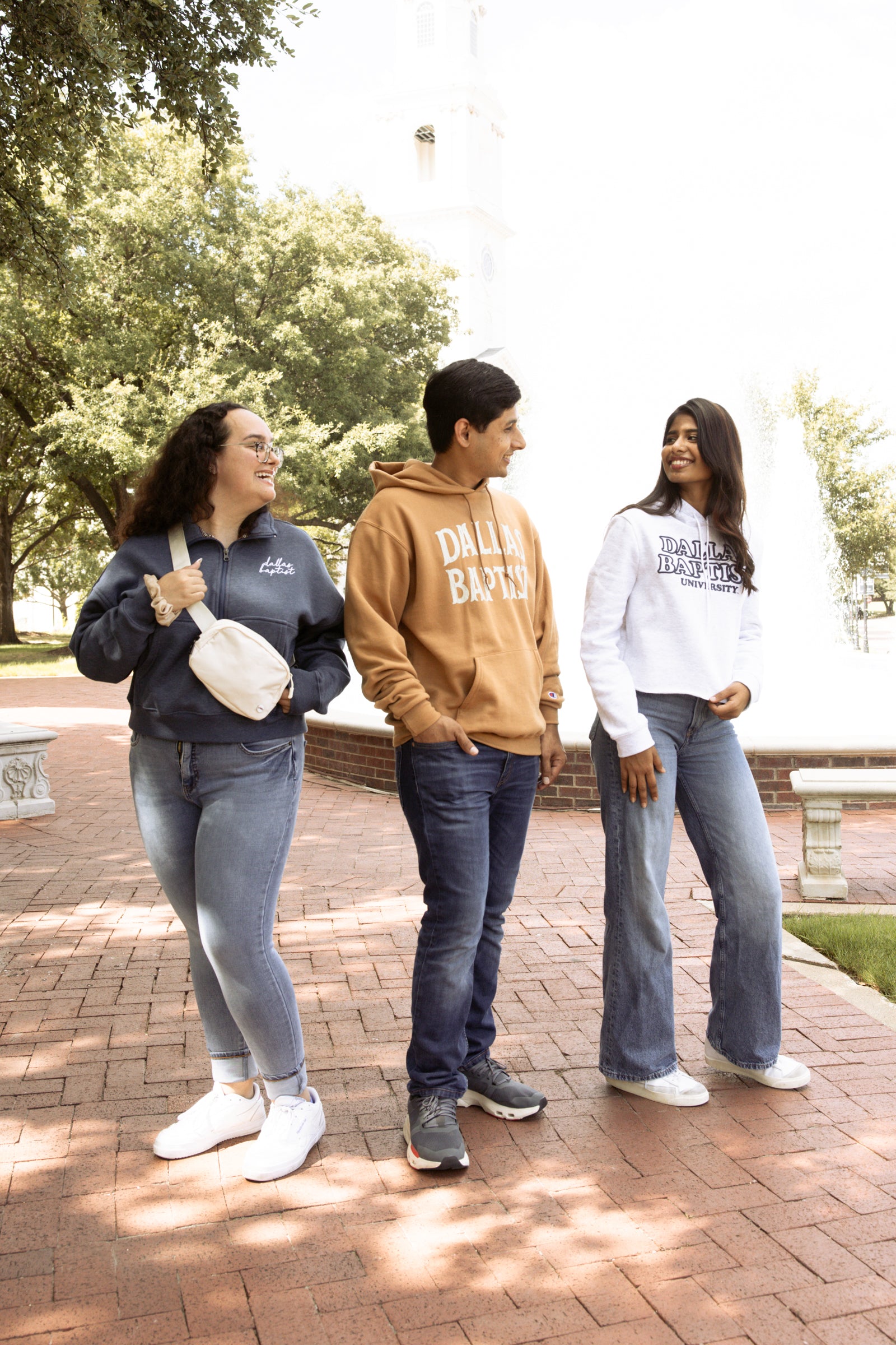 Three people standing on a brick path with trees in the background